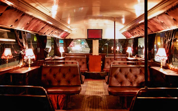 Interior of a vintage bus with dim lighting and plush seating for a Ghost Bus Tour.