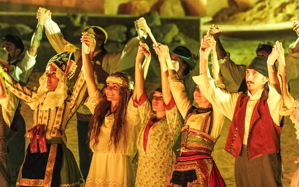 Performers in traditional costumes holding hands during The Dream of Toledo Night Show.
