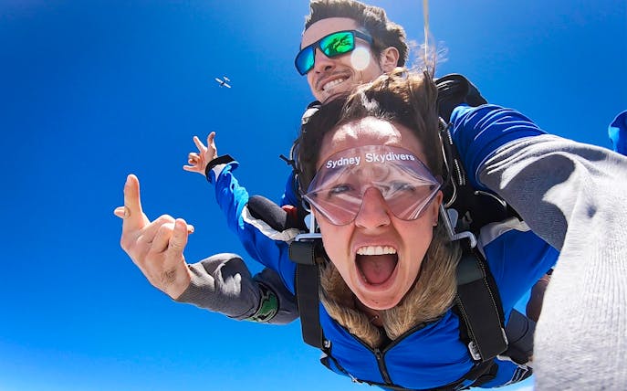 Tandem skydivers free-falling over Sydney with clear blue sky.