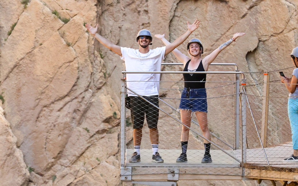 Tourists on a platform at Caminito del Rey with mountain backdrop, Malaga.
