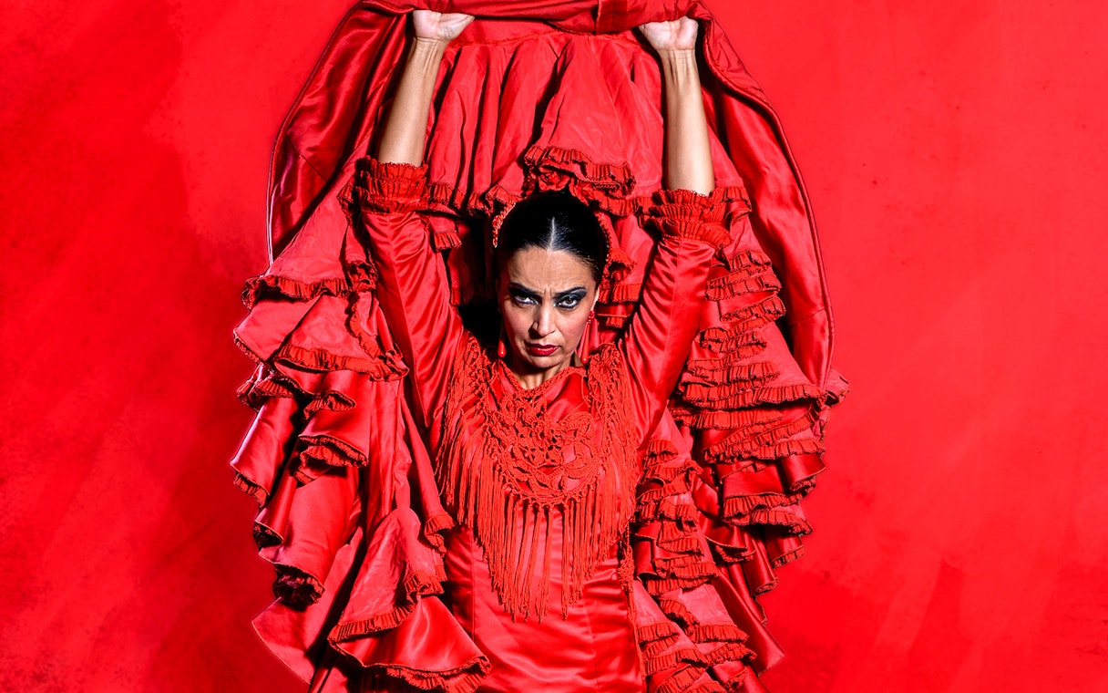 Flamenco dancer in red dress performing at Esencia espectáculo flamenco.