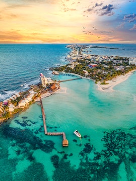 Aerial view of Isla Mujeres near Cancun, Mexico, with a sunset over the ocean.