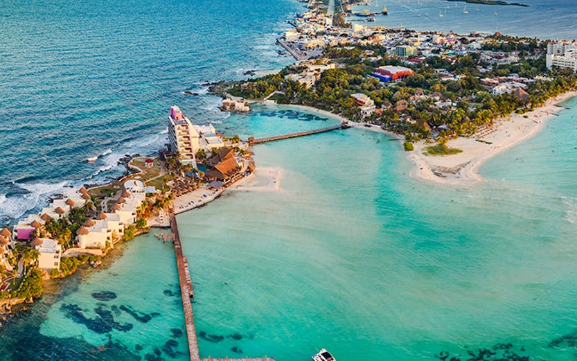Aerial view of Isla Mujeres near Cancun, Mexico at sunset with a pier and boat.