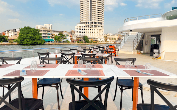 Tables set for dining on the deck of The Luxury White Dinner Cruise at ICONSIAM, Bangkok.