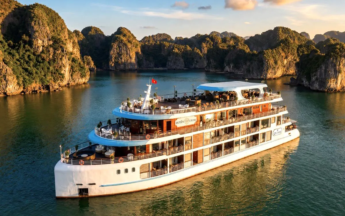 Luxury cruise ship sailing through Ha Long Bay with limestone karsts in the background.