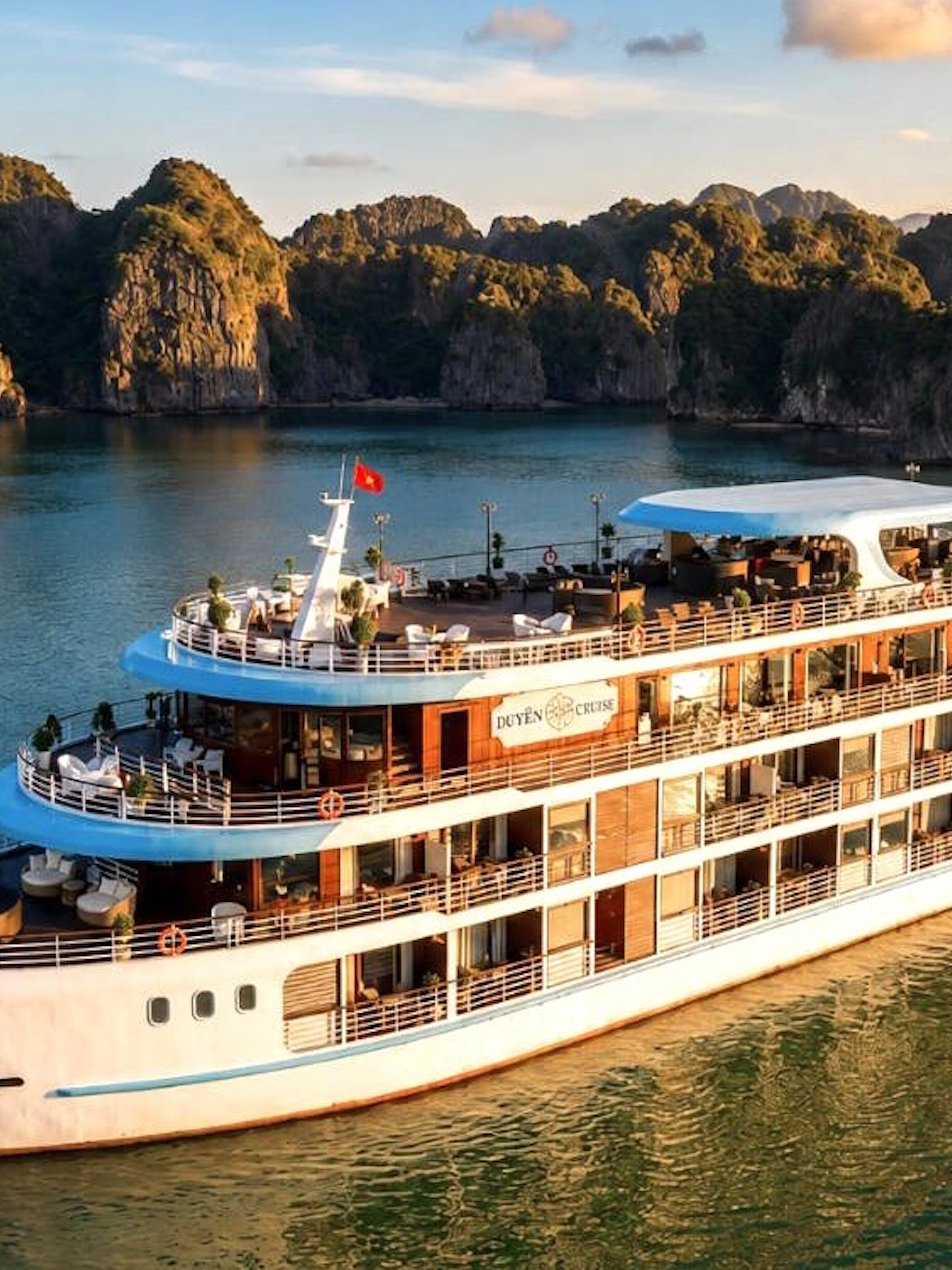 Luxury cruise ship sailing through Ha Long Bay with limestone karsts in the background.