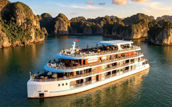 Luxury cruise ship sailing through Ha Long Bay with limestone karsts in the background.