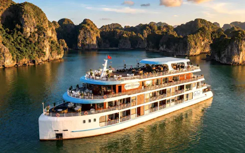 Luxury cruise ship sailing through Ha Long Bay with limestone karsts in the background.