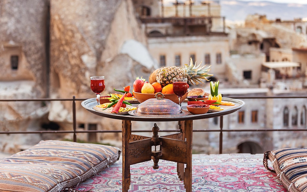 Traditional Turkish breakfast spread with fruits and drinks on a terrace in Cappadocia.