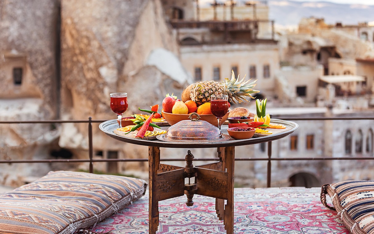 Traditional Turkish breakfast spread with fruits and drinks on a terrace in Cappadocia.