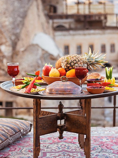 Traditional Turkish breakfast spread with fruits and drinks on a terrace in Cappadocia.