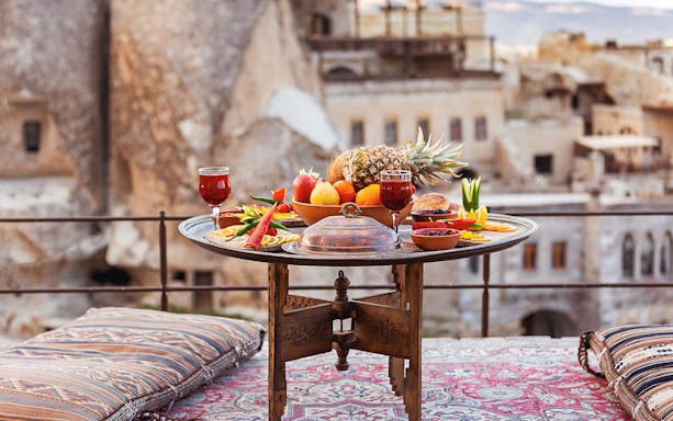 Traditional Turkish breakfast spread with fruits and drinks on a terrace in Cappadocia.