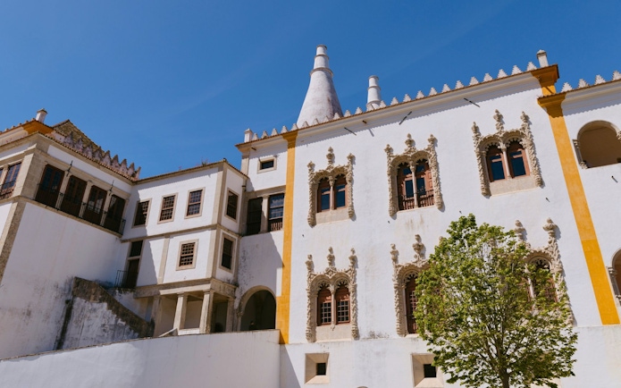 National Palace of Sintra with ornate windows and conical chimneys under a clear blue sky.