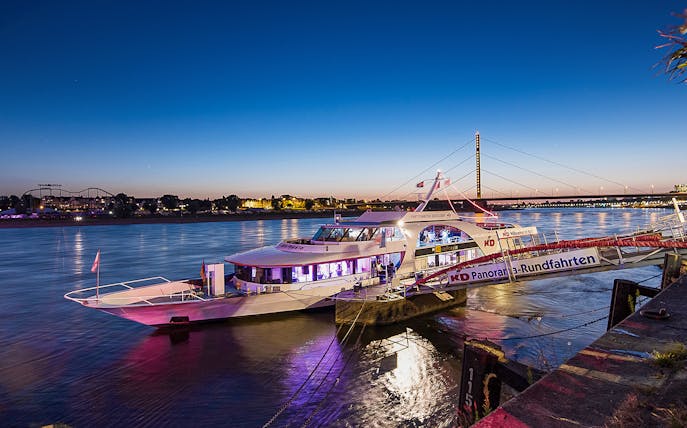 Cruise boat docked on the Rhine River at sunset in Düsseldorf, Germany.
