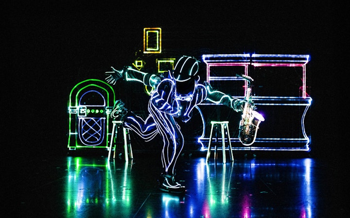 Performer in LED suit playing saxophone at iLuminate show.