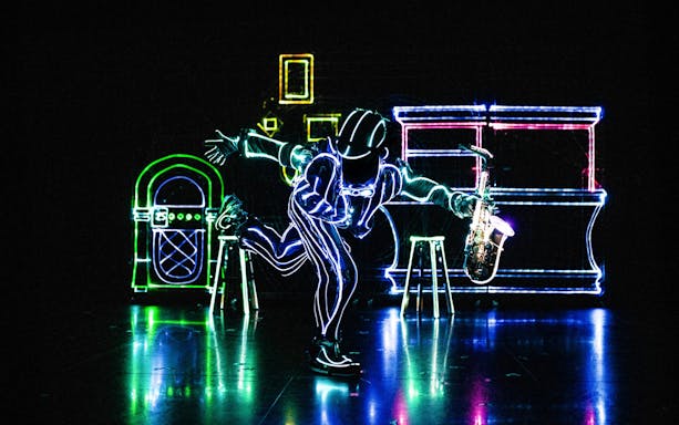 Performer in LED suit playing saxophone at iLuminate show.
