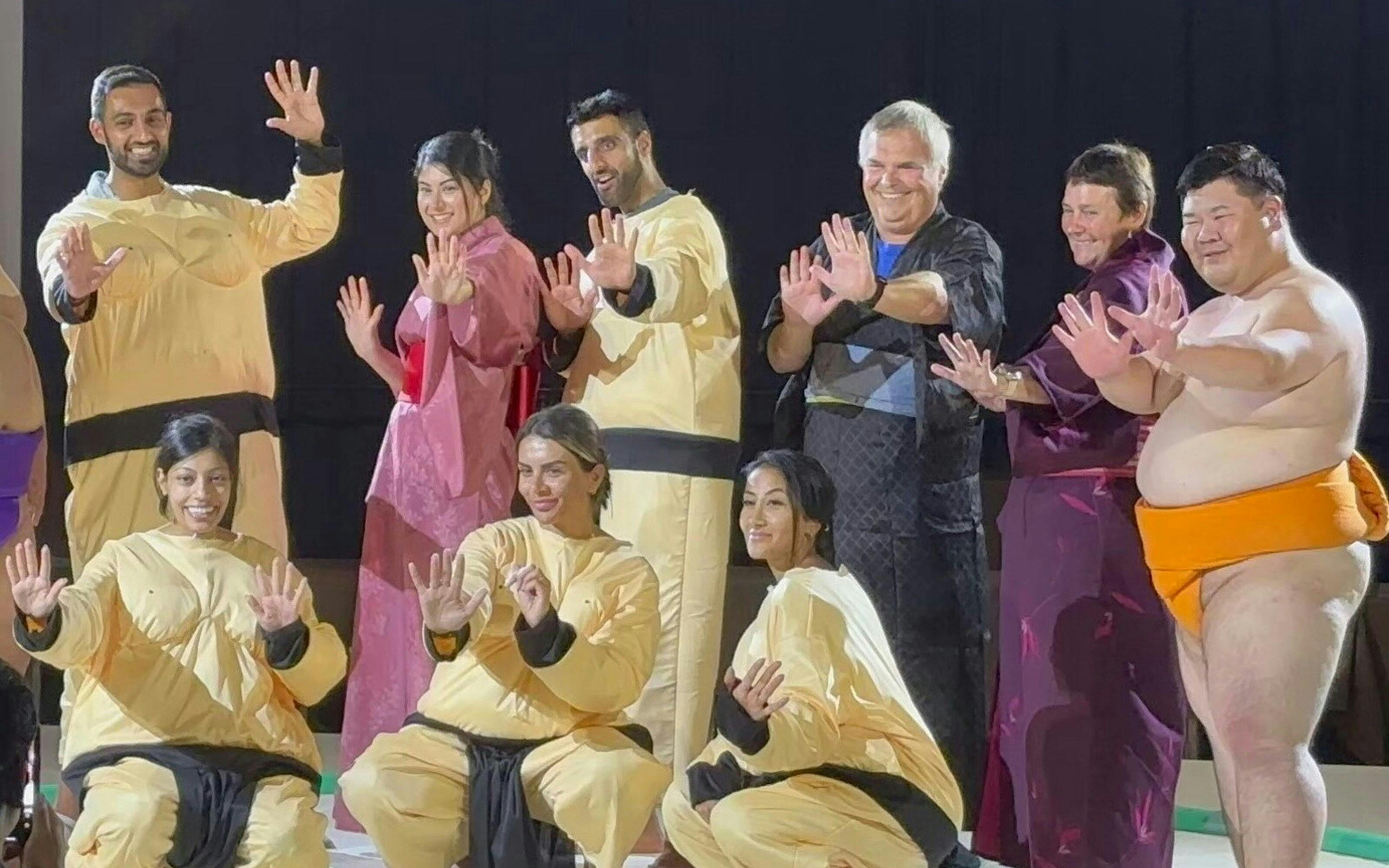 Sumo wrestlers and participants posing at Ochiizumibeya during a practice show with Chanko-Nabe hot pot.
