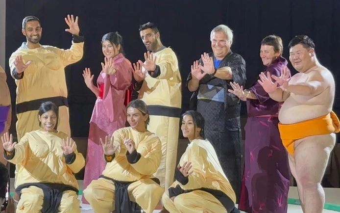 Sumo wrestlers and participants posing at Ochiizumibeya during a practice show with Chanko-Nabe hot pot.
