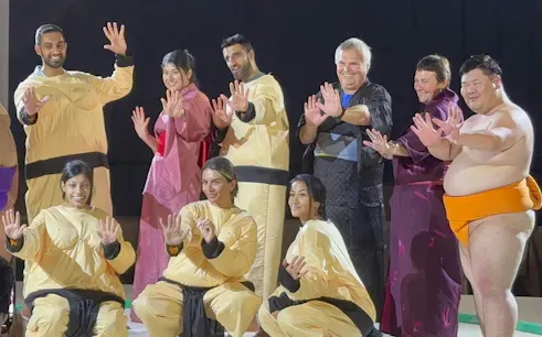 Sumo wrestlers and participants posing at Ochiizumibeya during a practice show with Chanko-Nabe hot pot.