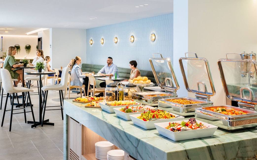 Buffet and seating area at Plaza Premium Lounge with guests dining.