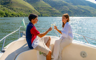 Tourist couple toasting wine on Douro Valley boat tour.