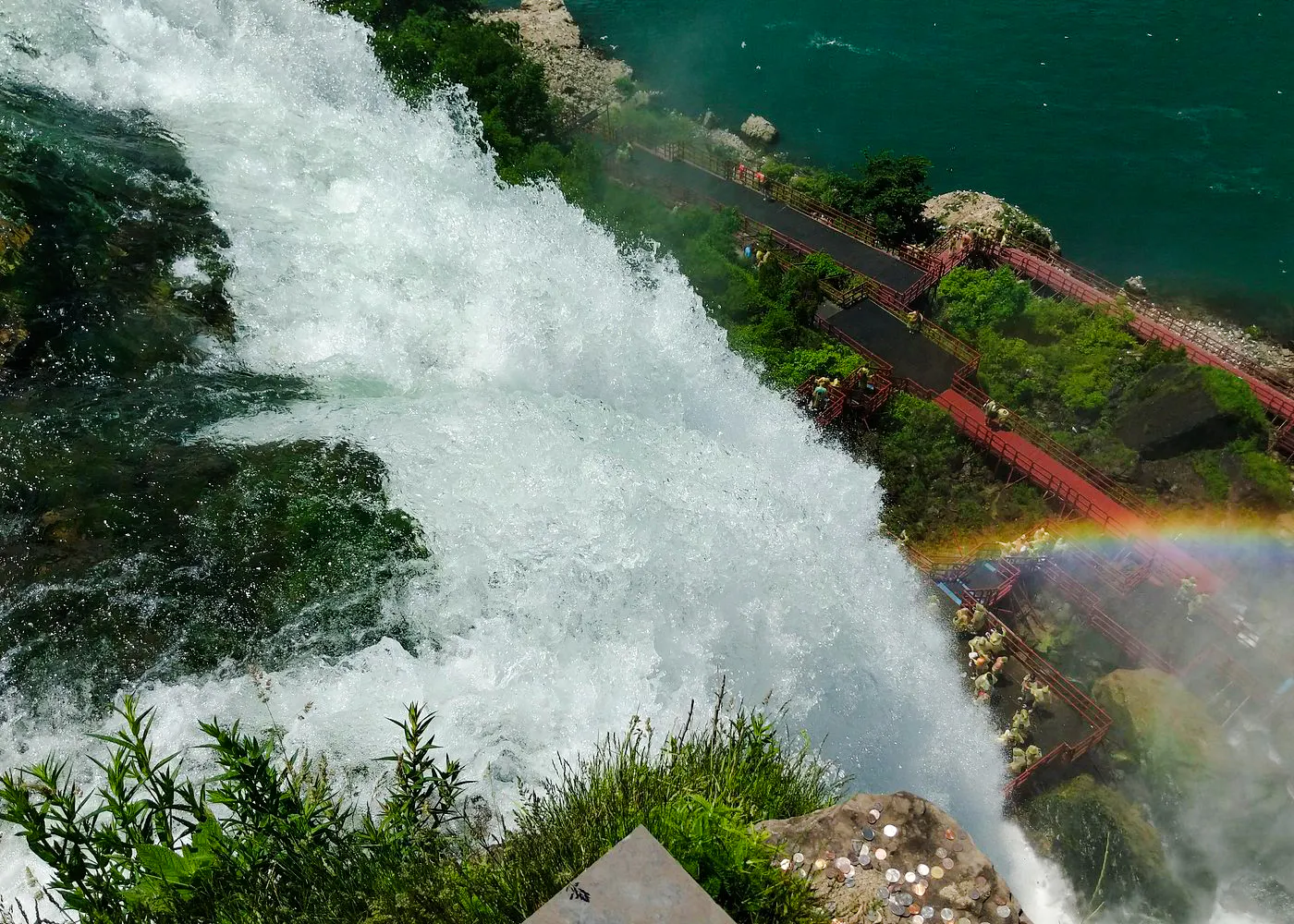 Niagara Falls view with rainbow and tourists on Cave of the Winds walkway, USA.