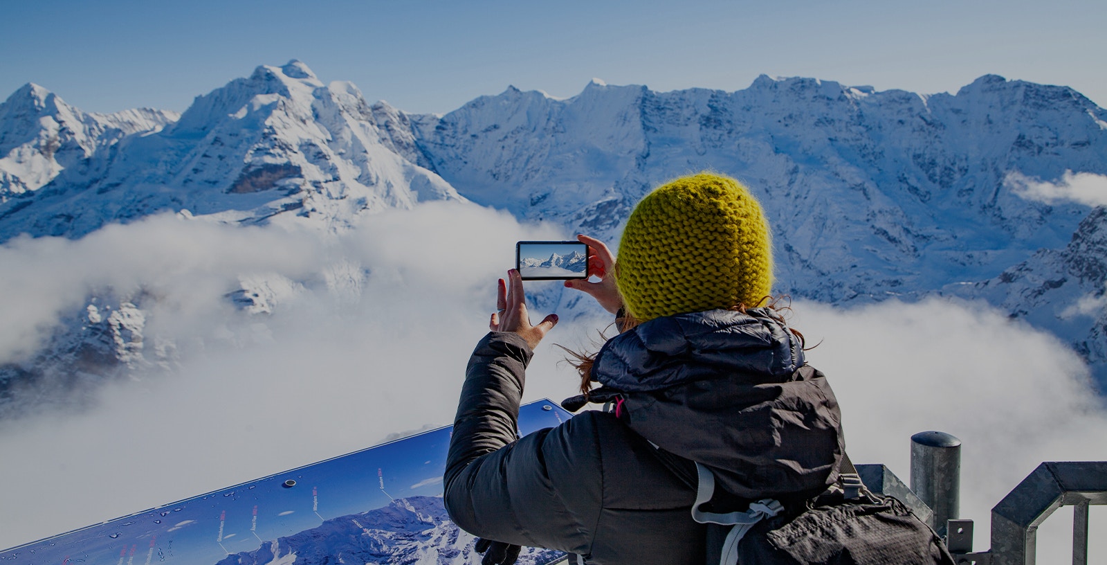 Person photographing snowy Alps on Zurich to Jungfraujoch tour.