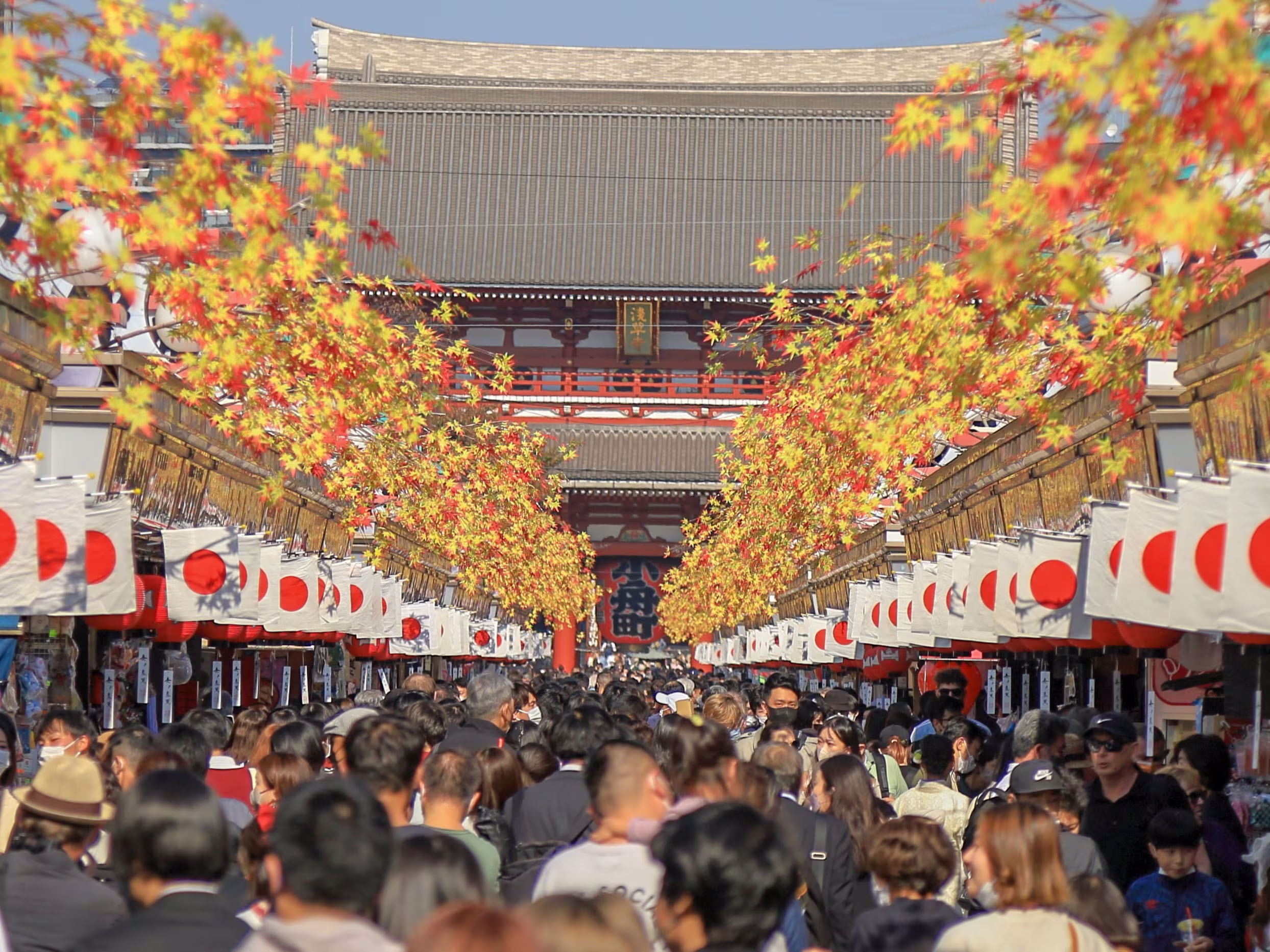 Crowded Nakamise-dori Street in Tokyo, Japan, with shops and Sensō-ji Temple in the background.