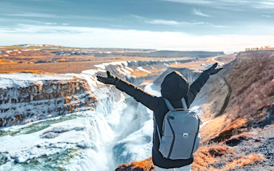 Person with arms raised overlooking Gullfoss waterfall on Golden Circle tour, Reykjavik.