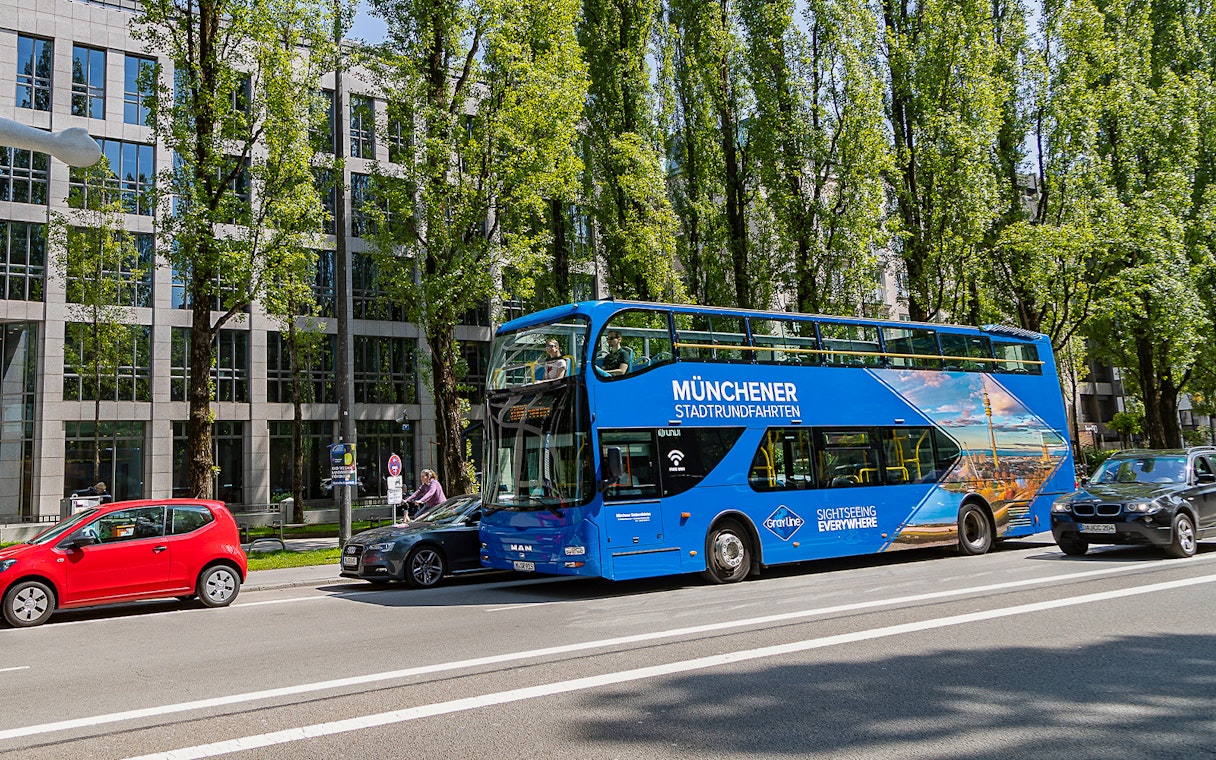 Blue double-decker bus on Munich street for Hop-On/Hop-Off Express Tour.