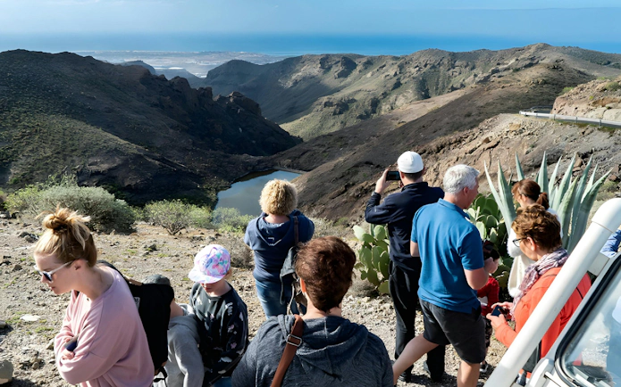 Tourists enjoying a scenic view of Gran Canaria's rugged landscape during a jeep safari.