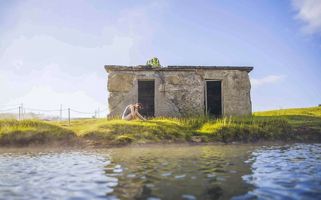 Guests relaxing by the water at Secret Lagoon Gamla Laugin, Iceland.