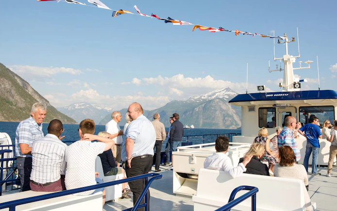 People enjoying a Geiranger fjord cruise with scenic mountain views in Norway.