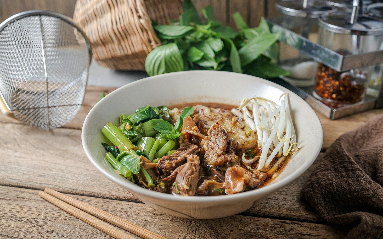 Stewed pork with thin rice noodles and vegetables in a bowl, garnished with bean sprouts.