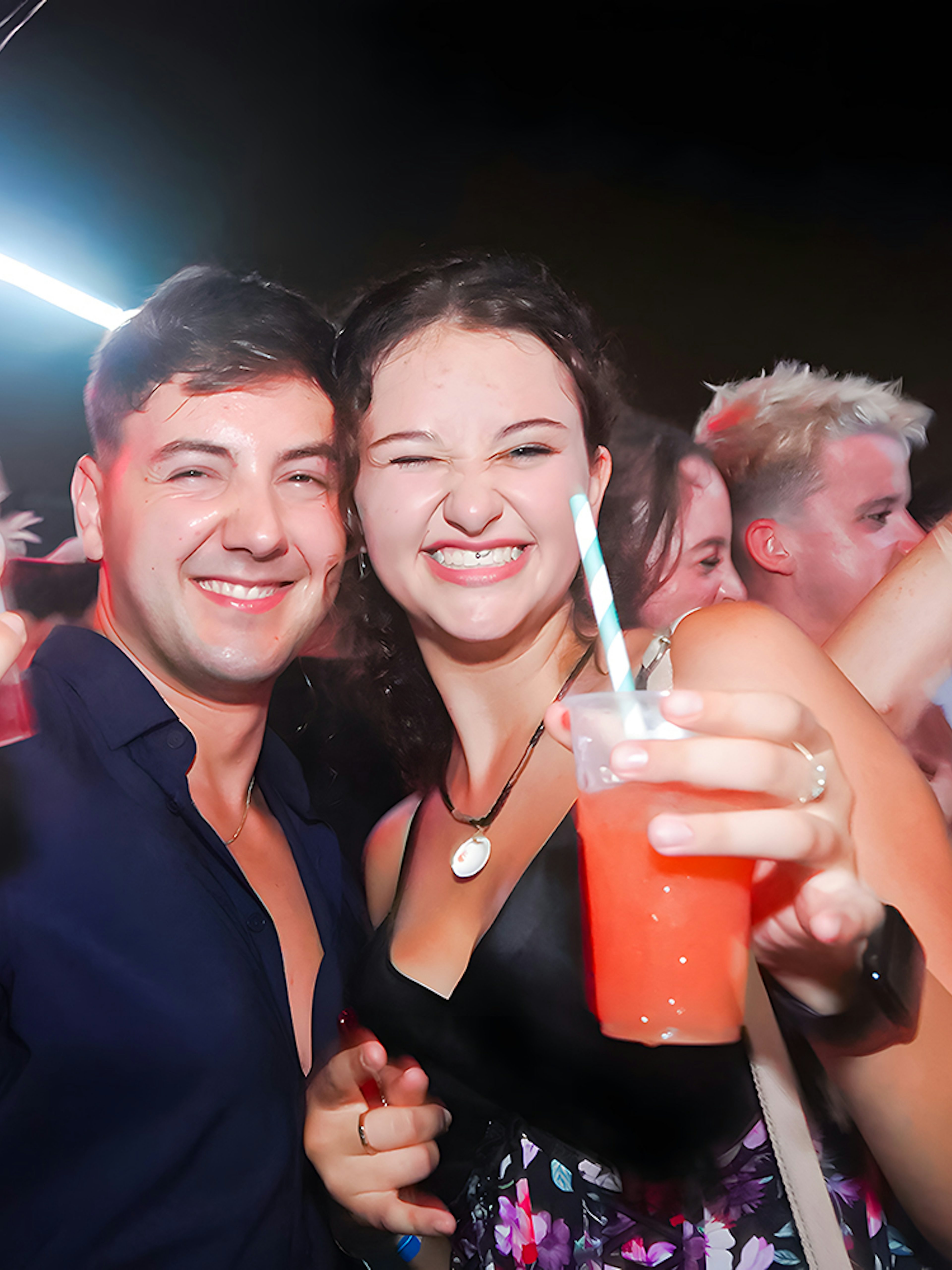Group enjoying drinks on a lively boat crawl at night.