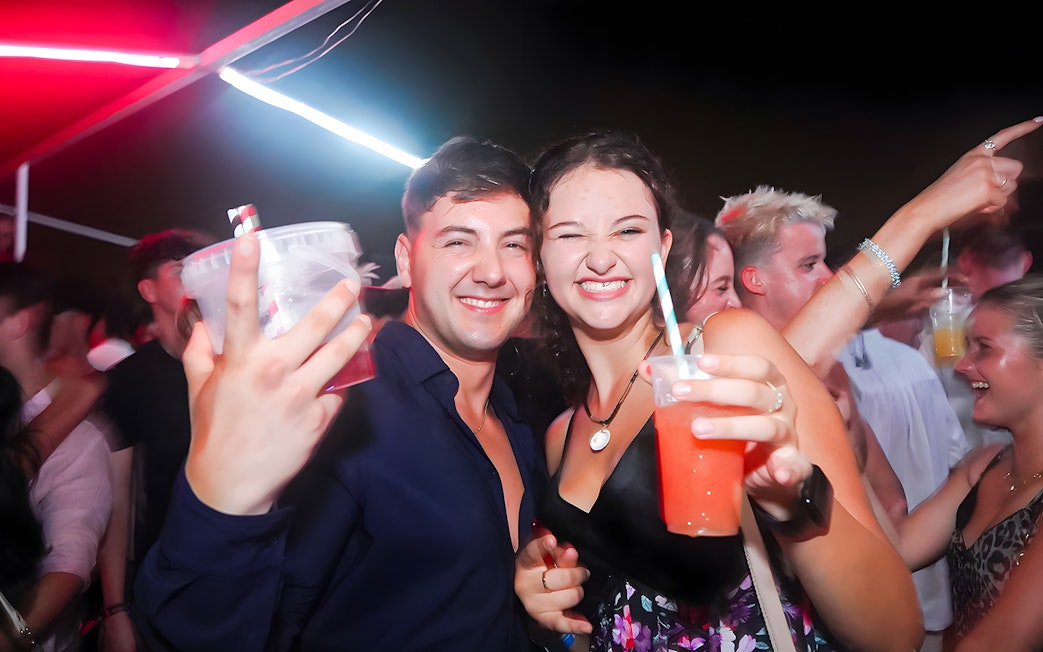 Group enjoying drinks on a lively boat crawl at night.