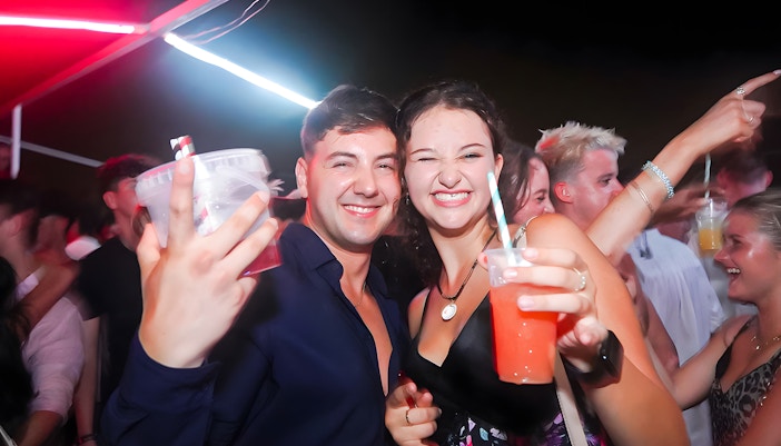 Group enjoying drinks on a lively boat crawl at night.