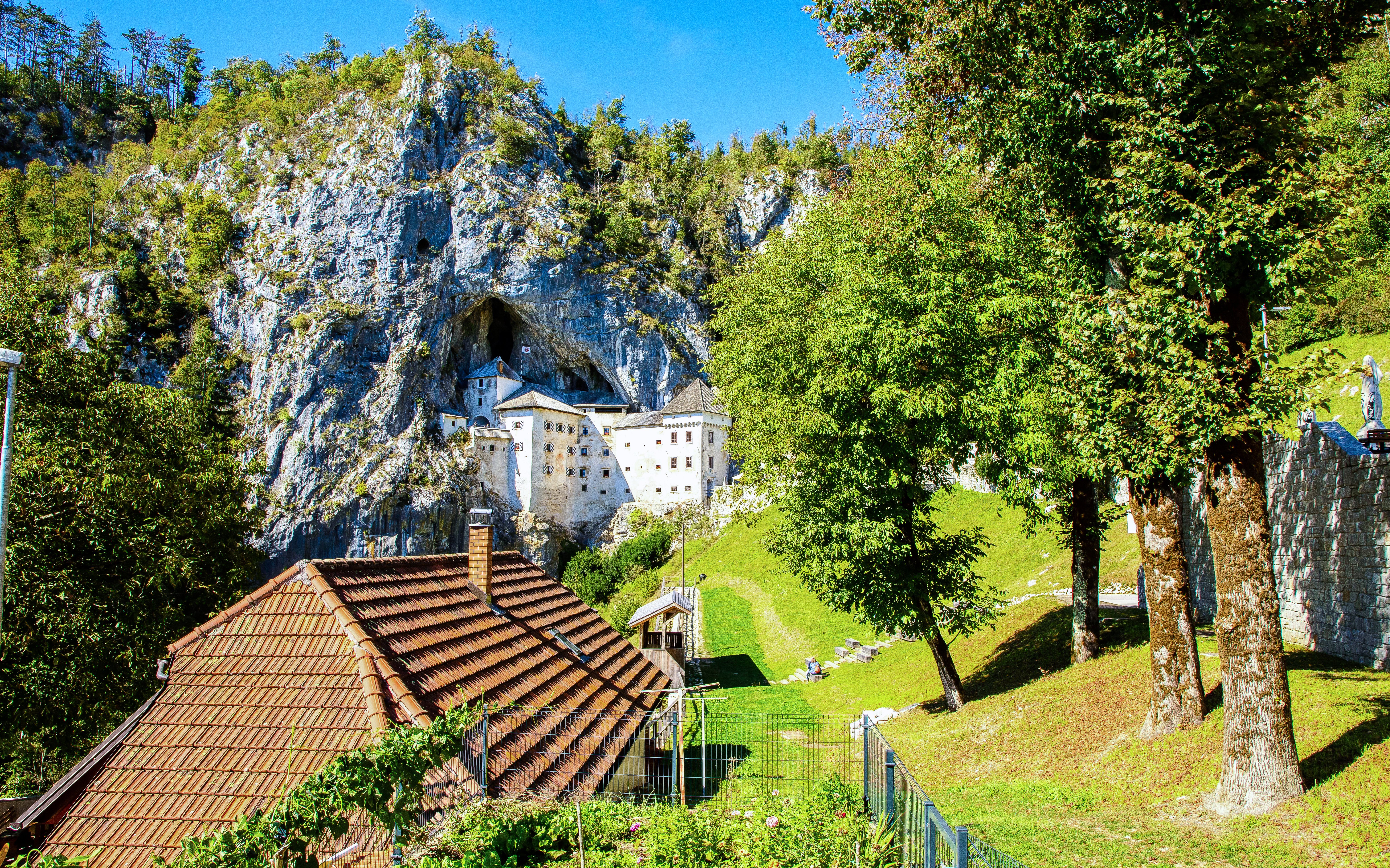 Predjama Castle built into a cliff with surrounding greenery in Slovenia.