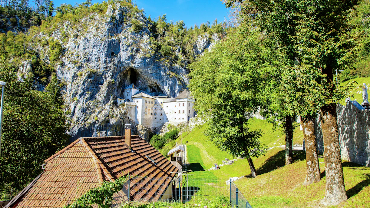 Predjama Castle built into a cliff with surrounding greenery in Slovenia.