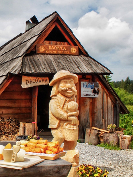 Traditional wooden hut in Zakopane with cheese display and carved figure.