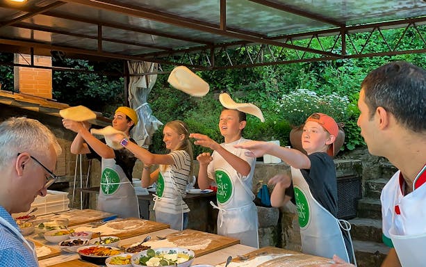 Participants tossing pizza dough at a Tuscany farmhouse cooking class near Florence.