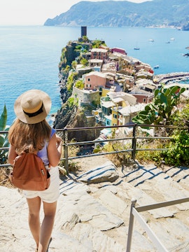 Backpacker descending steps with Vernazza view in Cinque Terre National Park, Italy.