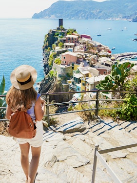 Backpacker descending steps with Vernazza view in Cinque Terre National Park, Italy.