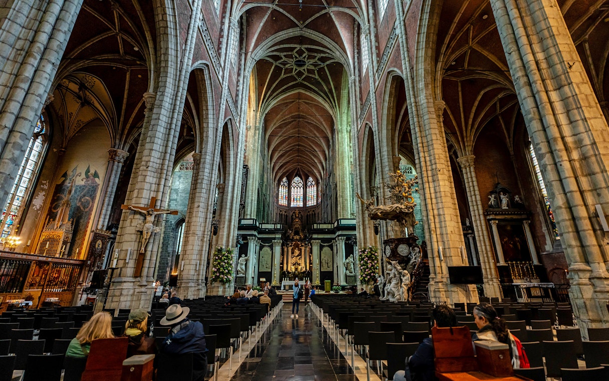 Interior view of Saint Bavo's Cathedral in Ghent, Belgium, showcasing its vaulted ceilings and ornate altar.
