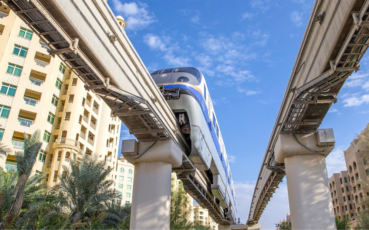 Palm Jumeirah Monorail passing between residential buildings in Dubai.