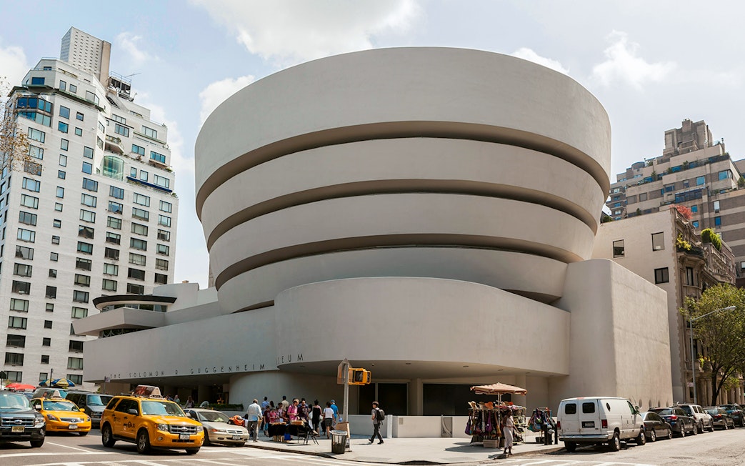 Guggenheim Museum exterior with visitors and yellow taxis in New York City.