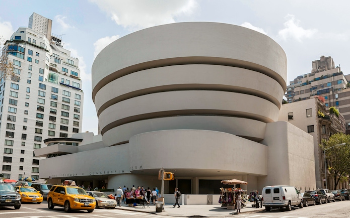 Guggenheim Museum exterior with visitors and yellow taxis in New York City.