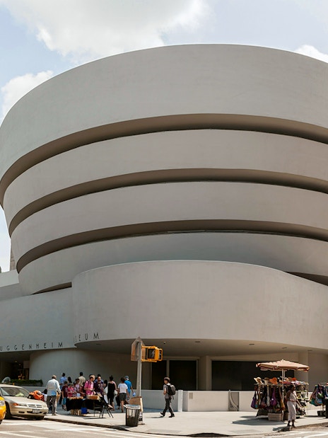 Guggenheim Museum exterior with visitors and yellow taxis in New York City.
