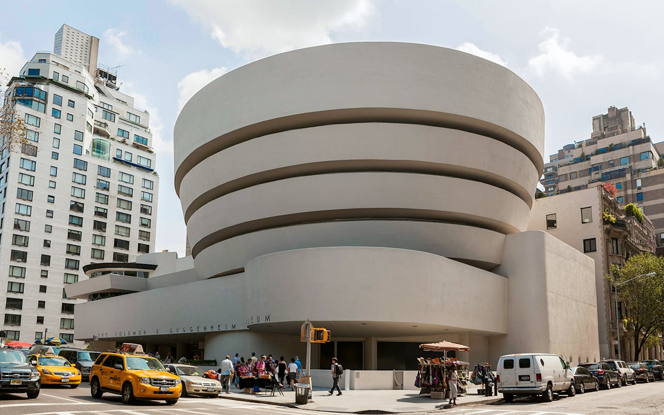 Guggenheim Museum exterior with visitors and yellow taxis in New York City.