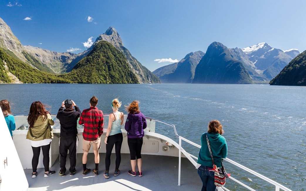 Tourists on a boat cruise in Milford Sound, New Zealand, viewing scenic fjords.